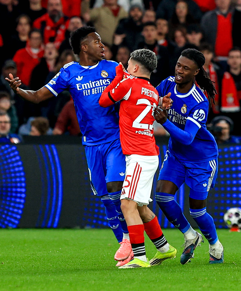 Джанлука Престианни (в центре) что-то говорит Винисиусу (слева), прикрыв рот футболкой